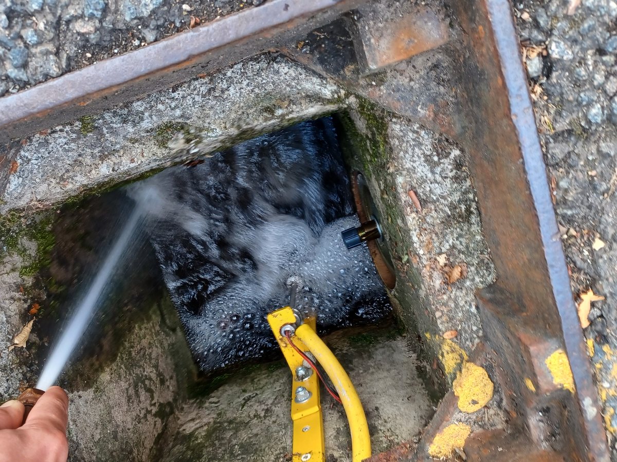 A flood sensor being tested with a hose in a drainage chamber